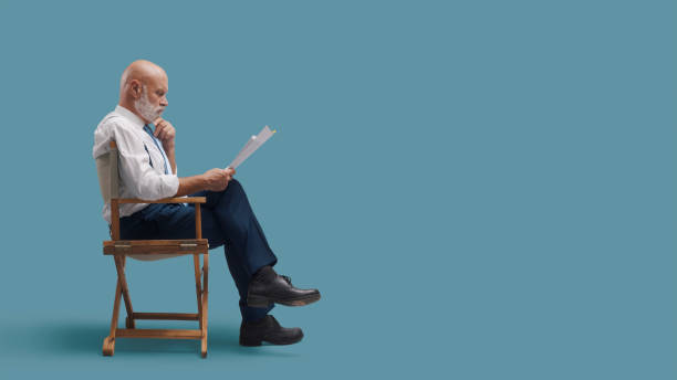 Professional film director sitting on the director's chair and reading the screenplay, film industry concept, blank copy space