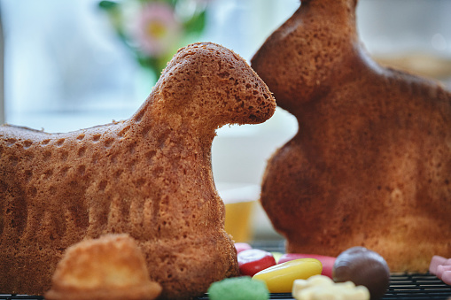 Crafted Easter bunny on the table for festive Easter celebration at home. Colorful Easter eggs in a basket and flowering willow decorated with Easter eggs on a gray background. Copy space for text.