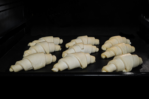 Nine croissants baking on tray in electric oven. French cuisine, homemade bakery, breakfast, food, cooking and pastry concept