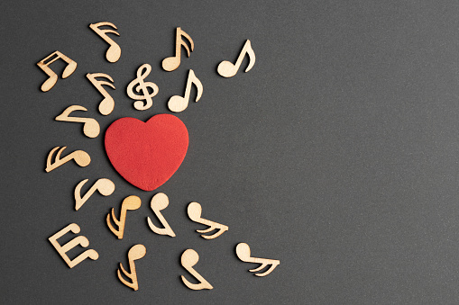 Musical wooden notes with heart, top view.