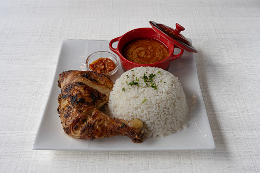 African dishe culinary Still Life. Chicken mafe with Grilled chicken, rice accompaniement and spicy sauce