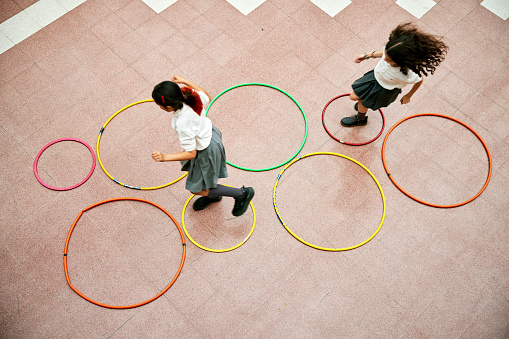 Two elementary schoolgirls playing hopscotch