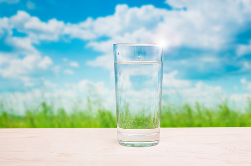 Water glass on grassland landscape background