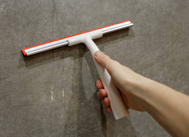istock A man removes water droplets with a plastic scraper. A man holds a plastic water scraper in his hand in close-up. 1459404609