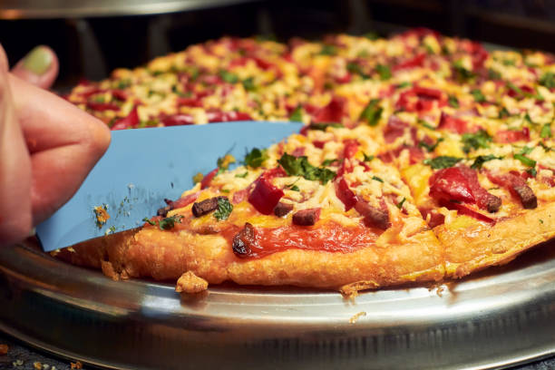 istock Cutting pizza into pieces. Woman cuts pizza close-up 1459408302