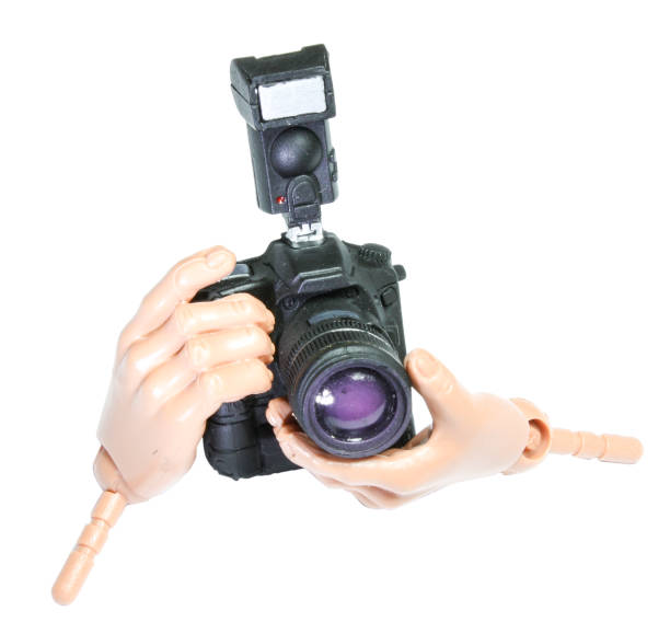 Miniature toy hands holding a photographic dslr on a white background cut out