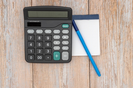 Calculator, blank notebook and pen on wooden background. Home economics. Family savings