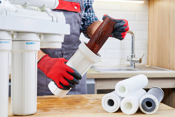 istock Plumber installs or change water filter. Replacement aqua filter. Repairman installing water filter cartridges in kitchen. Installation of reverse osmosis water purification system. 1459409650