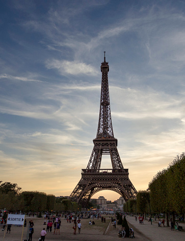 View of the world-renowned Paris Eiffel Tower with visitors on its grounds.