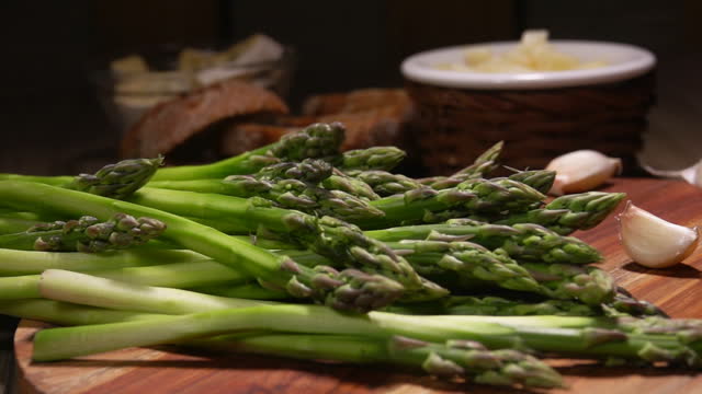 Peeled stalk of green asparagus attacks a bunch of asparagus