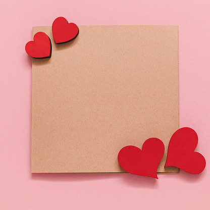 Greeting card with red wooden hearts on a pink background. Valentines Day concept. Top view. Copy space.