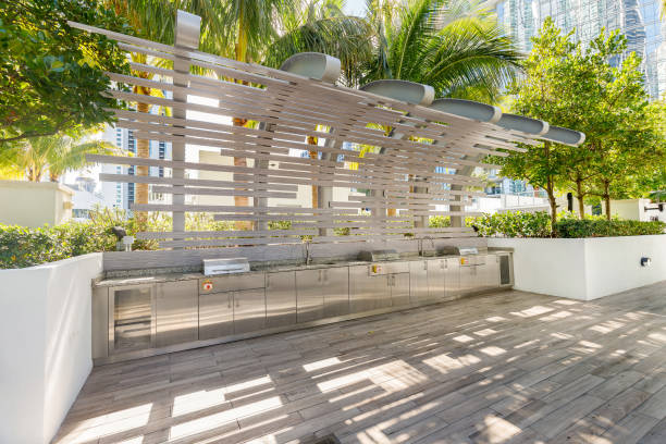 Beautiful outdoor kitchen Beautiful outdoor kitchen, modern and elegant in stainless steel, surrounded by tropical vegetation, wooden floor, elegant design structure in the background florida real estate house home interior stock pictures, royalty-free photos & images