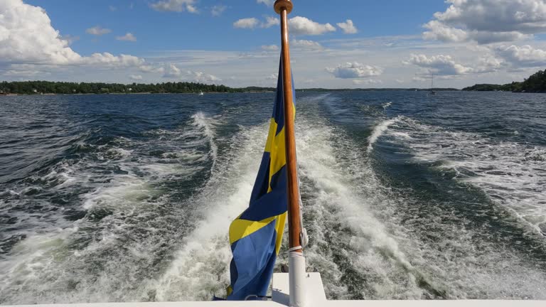 Swedish flag waving on rear of boat underway in Stockholm Archipelago. Flag is in the middle of video