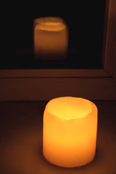 istock The yellow candle shines a warm light on the windowsill. 1459424381