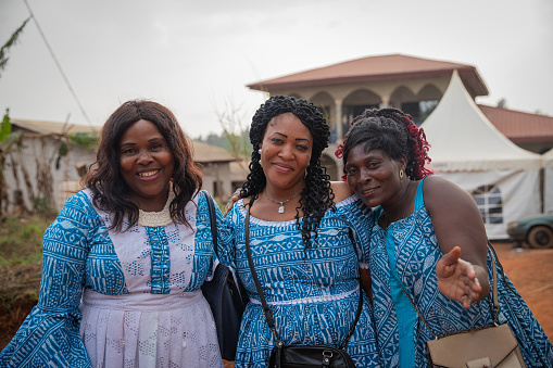 Three mature African women smiling together during a celebration in the village