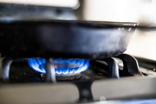 Horizontal shot of a white stove top with one hot burner and two off.  Shot at an angle.
