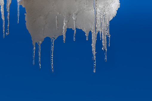 Ice icicles on the roofs of houses in winter.  winter atmosphere.  Consequences of the cold in the mountains.  Frozen water.