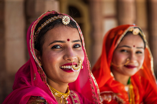 Young Indian women, wearing saris, posing in an Amber Fort near Jaipur, Rajasthan.  Amber Fort is located 13km from Jaipur, Rajasthan state, India. It was the ancient citadel of the ruling Kachhawa clan of Amber, before the capital was shifted to present day Jaipur.