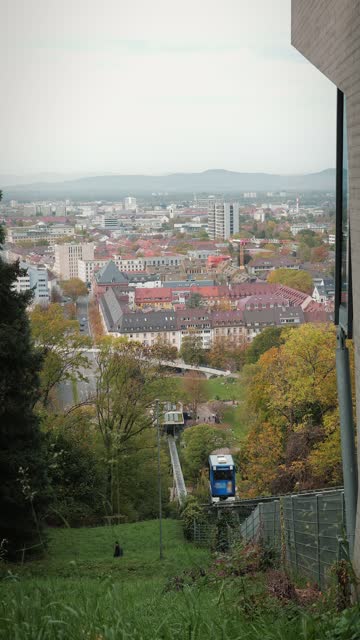 Funicular in Freiburg im Breisgau. Funicular cabin going down, vertical video. Funicular cabin going down along steep slope with view of Freiburg city on background