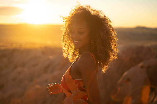 Portrait of young black woman with curly hair smiling at sunset stock photo