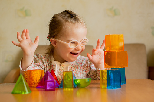 A girl with Down's syndrome lays out geometric shapes at home