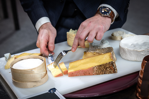 a waiter is cuting a cheese for his client in a hotel