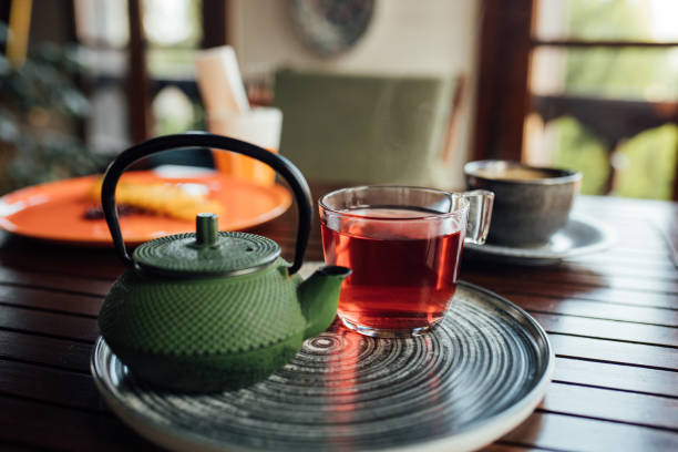 Iron teapot and a cup of herbal tea on table