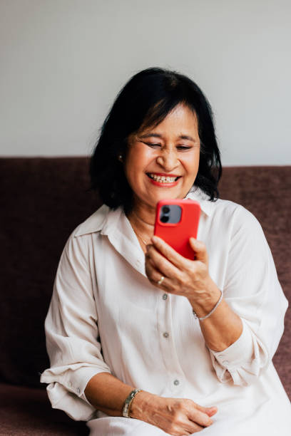 istock A Happy Beautiful Senior Woman Enjoying Watching Something On Her Mobile Phone While Relaxing At Home 1459436717