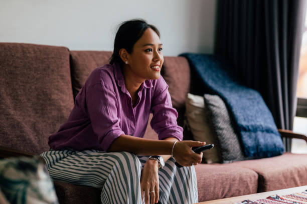 A Happy Beautiful Woman Watching TV While Relaxing At Home