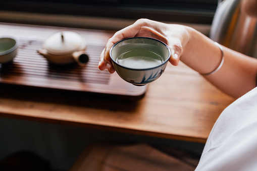 A from above view of an anonymous Asian female drinking tea while relaxing.