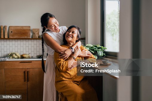istock A Happy Beautiful Woman Hugging Her Mother While She Is Sitting In The Kitchen And Drinking Tea 1459436747