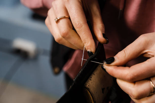 istock Craftsman sews genuine leather using needle and thread for creation natural leather products. Equipment for genuine leather production in workshop. Process of stitching genuine leather. 1459438265