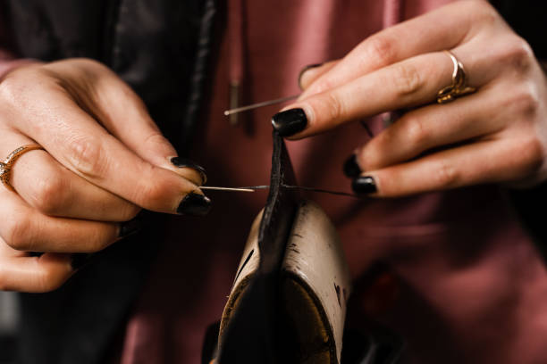 istock Craftsman sews genuine leather using needle and thread for creation natural leather products. Equipment for genuine leather production in workshop. Process of stitching genuine leather. 1459438266