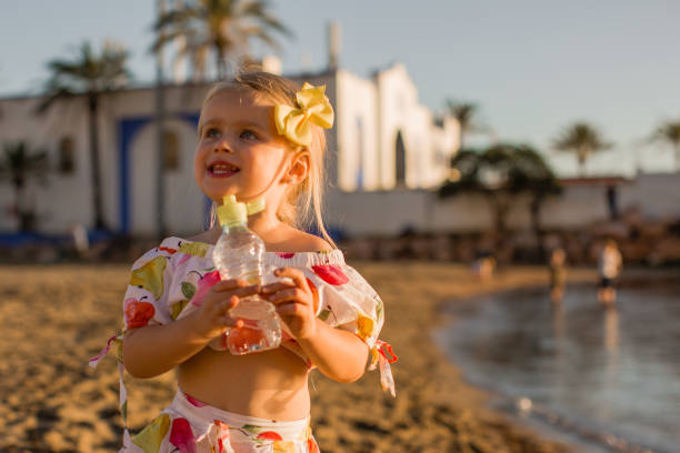 Little girl drinking water on the beach