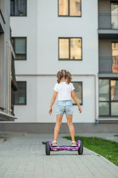 Photo of Child girl riding in on gyroscooter. Hobbies and active lifestyle in city.