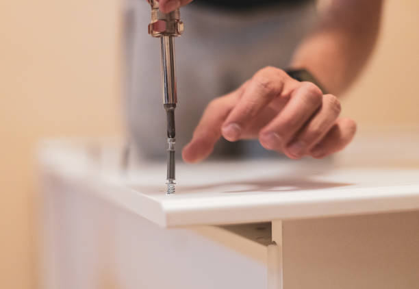 istock A young man is screwing a screw into a board with a screwdriver. 1459442178