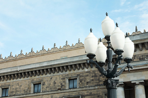 Old fashioned street light lamp near building against cloudy sky