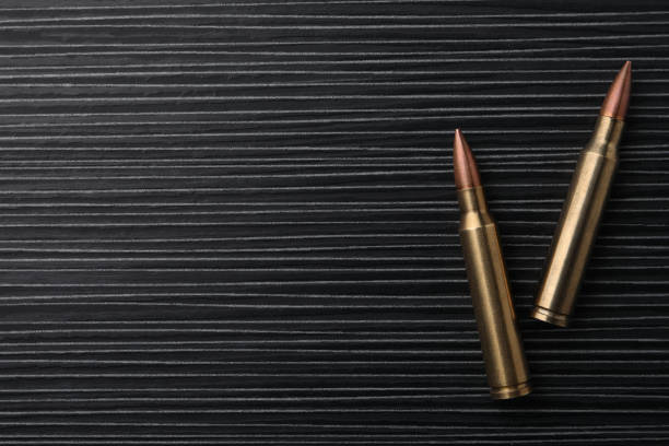 две пули на черном деревянном столе, плоско лежали. место для текста - bullet ammunition rifle gun стоковые фото и изображения
