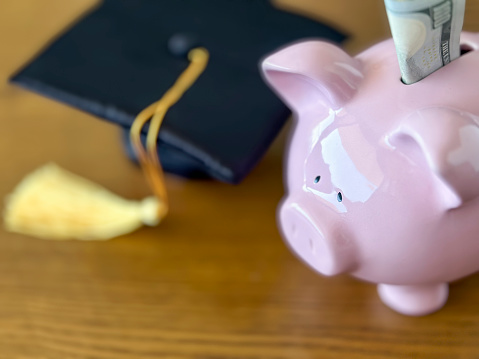 Piggy bank with 
mortarboard and 100 dollar bills