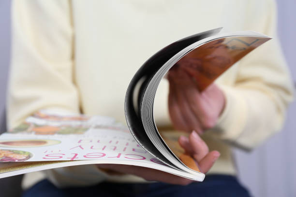 Woman reading magazine on light grey background, closeup
