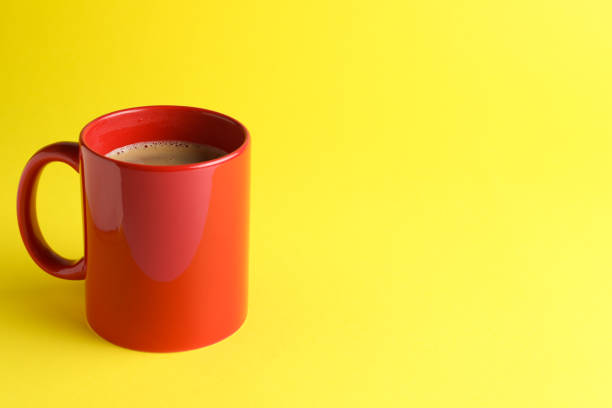 istock Red mug of freshly brewed hot coffee on yellow background, space for text 1459446727