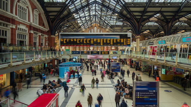 Commuter and passenger at London Liverpool Street Train Station with departure board- 4k time-lapse (tilt-up)