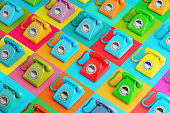 Array of retro rotary telephones in saturated colours on high colour contrast background. Illustration of the concept of telemarketing, call centers, cold calls and communication