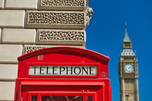 Red telephone booth in London with Big Ben on background.