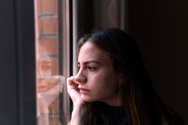 istock Unhappy woman looking out window 1459451525