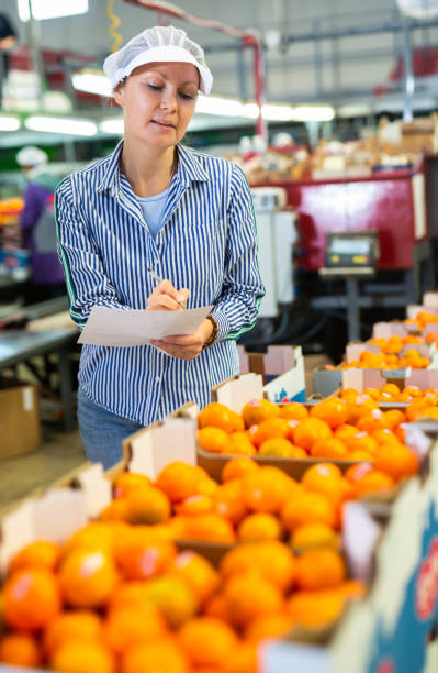 istock Positive female worker fills out a document at a citrus processing plant. 1459451666