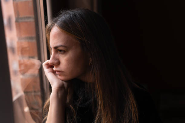 istock Upset woman looking out window at home 1459451844