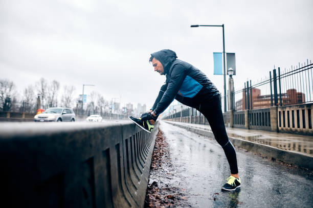 istock Athletic man tying shoelace on sneakers while running in the rain. 1459453310