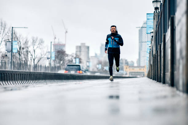 istock Full length of athlete jogging on city streets while it's raining. 1459453320