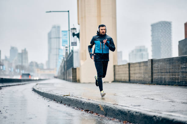 istock Determined runner jogging on city street in the rain. 1459453347